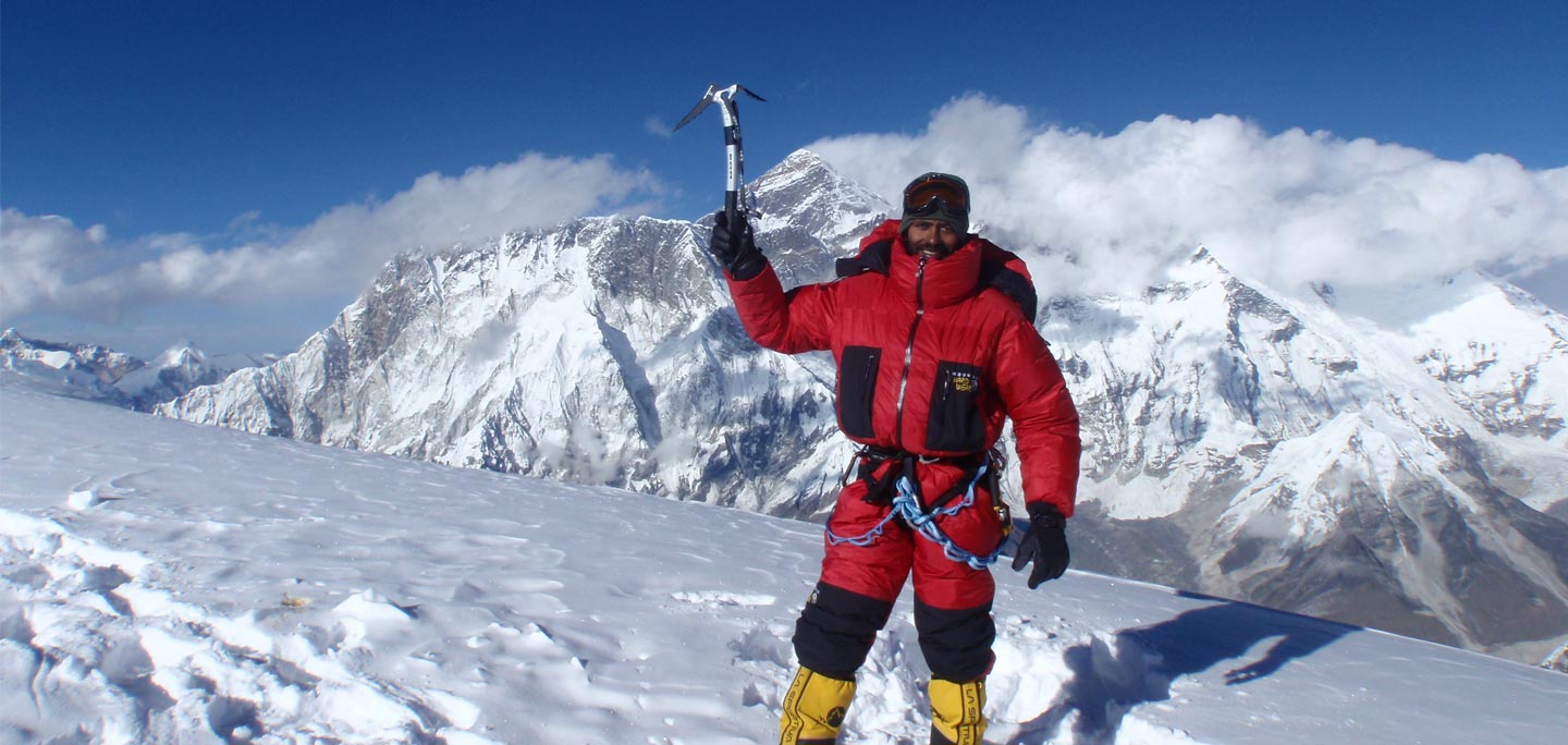 one ama dablam climber wearing red mountaineering jaket, mountaineering boot, gloves and He is holding one hand ice axe with smilling face